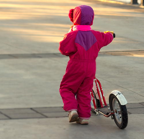 Flicka leder en sparkcykel.